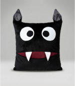 A square black plush monster pillow with two pointy ears on top. It features large, surprised white eyes and a wide mouth with a deep red interior and two sharp white fangs. The mouth functions as a pocket for storage.