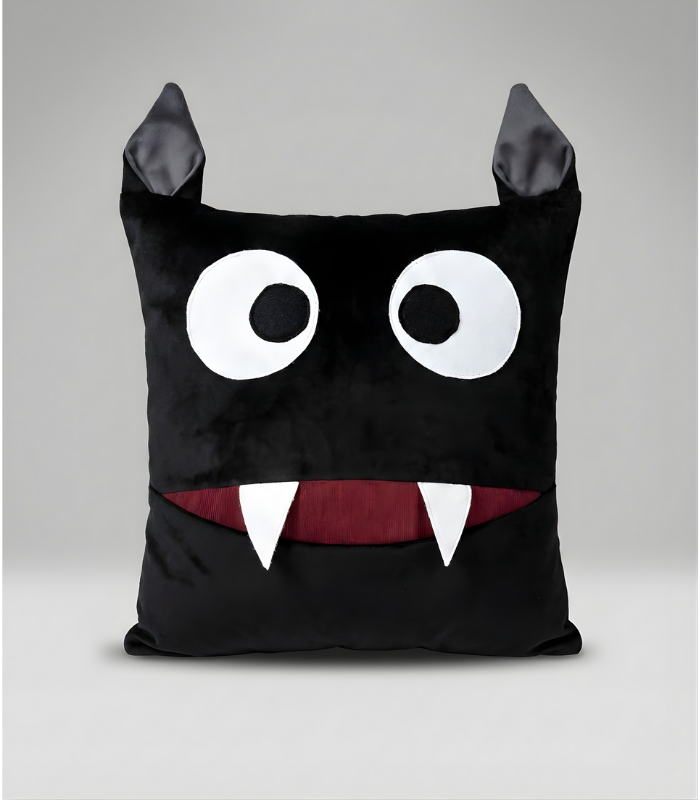 A square black plush monster pillow with two pointy ears on top. It features large, surprised white eyes and a wide mouth with a deep red interior and two sharp white fangs. The mouth functions as a pocket for storage.